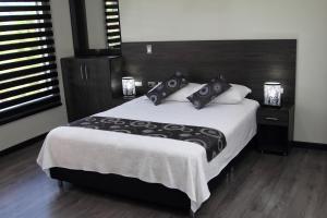 SibundoyTL Casa Blanca Hotel Boutique Sibundoy Putumayo的一间卧室配有一张大床,提供黑白枕头