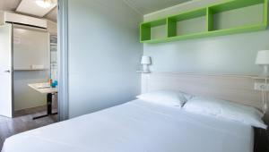 博格利斯科Camping Genova Est的卧室配有白色的床和书桌