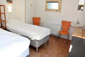 福尔登尔福波斯冈斯特乡村民宿的配有2张床的带水槽和2把橙色椅子的客房