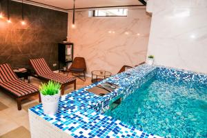 加格拉Grand Hotel Gagra的一个带蓝色瓷砖的泳池和两把椅子