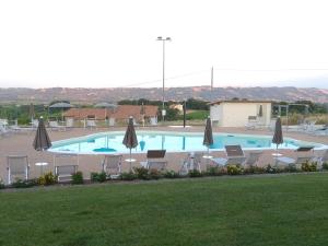 Mozzagrogna伊甸园公寓式酒店的一个带椅子和遮阳伞的大型游泳池