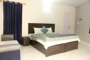 新德里Comfort Point Bed & Breakfast的一间卧室配有一张带蓝色窗帘的床和一把椅子