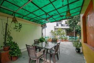 新德里Comfort Point Bed & Breakfast的一个带桌椅和绿色天篷的庭院