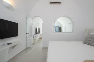 阿克罗蒂里Santo Castello的白色的客房配有床和电视。