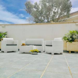 玛丽娜迪曼卡维萨Residence Le Palme的庭院设有白色的椅子和植物,墙壁为白色