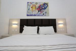 佩科霍里莱帕斯公寓的卧室配有白色床,上面有绘画作品