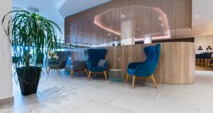 伍珀塔尔Flemings Hotel Wuppertal-Central的一间设有蓝色椅子和盆栽植物的等候室