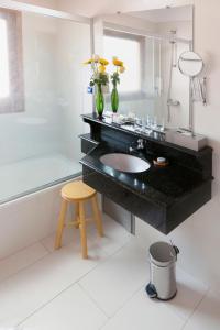 亚松森韦斯特法伦豪斯酒店的浴室设有黑色柜台、水槽和凳子