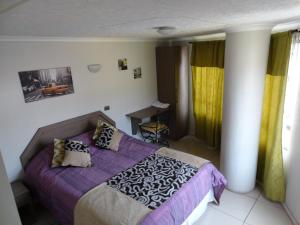 安托法加斯塔Hostal Quinta Normal的一间卧室配有一张带紫色床单和枕头的床。