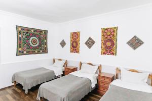 撒马尔罕Trip.LE Hostel Samarkand的一间设有三张床的客房,墙上挂有绘画作品