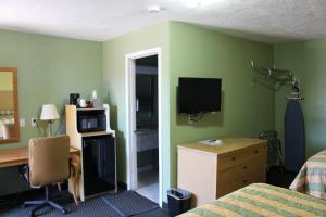 斯托克顿堡Deluxe Inn Fort Stockton的一间卧室设有绿色的墙壁、一张桌子和一张床