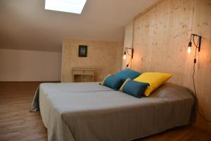 马洛塞讷Le pigeonnier的一间卧室配有一张带蓝色和黄色枕头的大床
