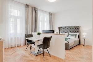 布拉格Gold Art Apartments的白色的客房配有一张床、一张桌子和椅子