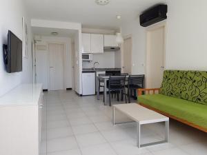 贝尼多姆玛丽亚维多利亚公寓的一间带绿色沙发的客厅和一间厨房