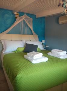 斯卡拉波塞冬公寓的一间卧室配有绿床和毛巾