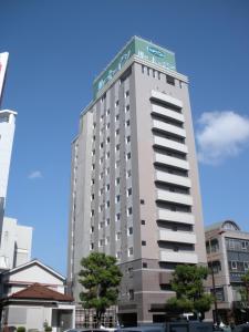 宫崎Hotel Route-Inn Miyazaki Tachibana Dori的一座高大的建筑,上面有标志