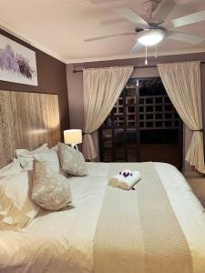 赫卢赫卢韦The Wilds Guest House的卧室配有一张白色大床和吊扇