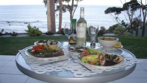 莫里莫科Mollymook Beach Waterfront的一张桌子,上面放着两盘食物和一瓶葡萄酒