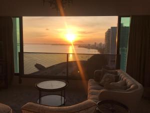 乔治市SUNRISE Gurney Seaview Luxury Duplex的客厅配有沙发和享有日落美景的窗户。