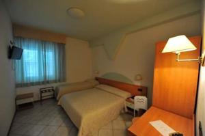 巴斯蒂亚乌姆布拉Hotel Il Cammino Di Francesco的一间卧室配有一张床、一张桌子和一盏灯