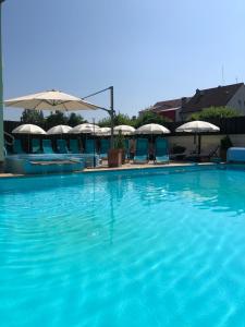 皮耶什佳尼戴安娜旅馆的一个带椅子和遮阳伞的大型蓝色游泳池