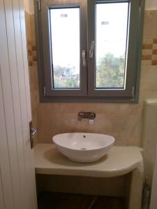 纳克索乔拉Infinity Apartments的一间带白色水槽的浴室和两个窗户