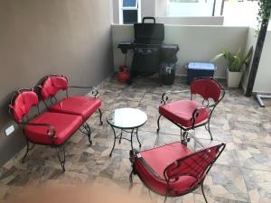 圣地亚哥洛斯卡巴Aprtamento Deluxe Santiago, Residencial Palma Real R402的客厅配有红色椅子和桌子