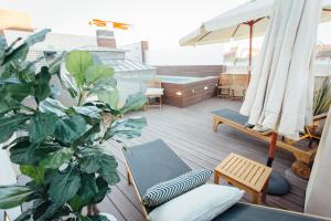 塞维利亚One&Lux Byron Suites的阳台种有植物,设有热水浴池和雨伞。