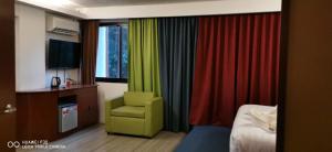 爱妮岛Villa Israel Ecopark El Nido的酒店客房带绿椅和色彩缤纷的窗帘