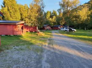 IsfjordenRomsdalseggen Camping的一条土路,有房子和停在田野的汽车