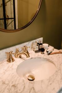 金斯顿罗斯蒙特宾馆的浴室水槽设有金色水龙头和镜子