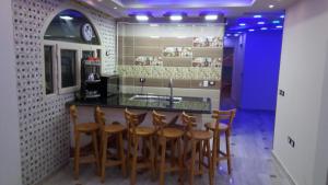 马特鲁港Al-Madina Tower Apartments的厨房设有酒吧、木椅和水槽