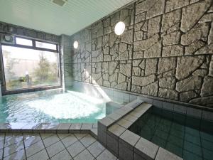 岛田岛田吉田国际鲁特因酒店的浴室配有带石墙的大浴缸