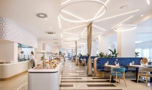 拉布Valamar Carolina Hotel & Villas的一间设有蓝色桌椅的餐厅和一间自助餐厅