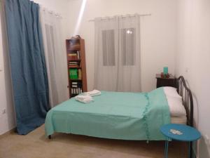 PlatánaKymi Bay House的一间卧室设有一张绿色的床和一个书架