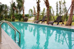 是拉差Porestva Hotel Sriracha的一个带椅子的游泳池,棕榈树