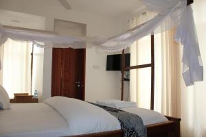 达累斯萨拉姆Villa Dahl Beach Resort的一间卧室配有一张带天蓬和窗户的床