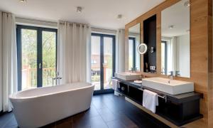 吕本斯特兰豪斯酒店 - 精品SPA度假酒店的带浴缸、两个盥洗盆和镜子的浴室