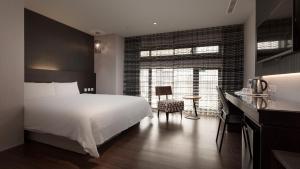 高雄好地方大饭店三多馆的卧室配有白色的床、书桌和窗户。
