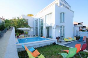 普拉Villa Andrea的白色的房子,设有游泳池和椅子