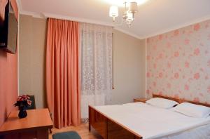 第比利斯Bellis的一间卧室配有床和橙色窗帘的窗户
