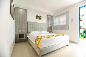 萨兰托Hotel El Jardin的一间卧室配有一张大白色的床和色彩缤纷的毯子