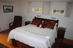 KaikohePaheke Boutique Lodge的一间卧室配有一张床和一把椅子,还有两个窗户