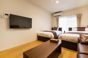 别府Cocolie BEPPU的酒店客房设有两张床和一台平面电视。