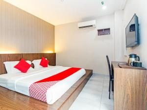 Kampong Batu BelahSuper OYO 340 Comfort Hotel的一间卧室配有一张带红色枕头的床和一台电视。