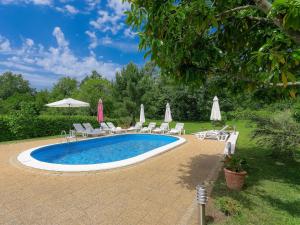 VinežHoliday Home Lucija by Interhome的庭院内带椅子和遮阳伞的游泳池