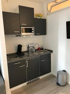 汉堡Apartmenthaus Hamburg Eppendorfer Weg的厨房配有黑色橱柜、水槽和微波炉