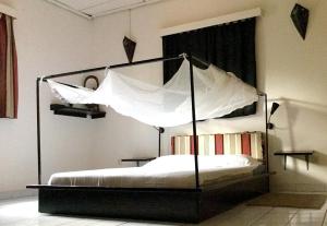 巴马科Auberge Djamilla的卧室配有带白色床单的天蓬床