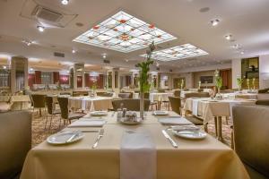 维尔纽斯艺术中心酒店的餐厅设有白色的桌椅和天窗