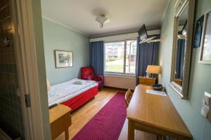 卡亚尼卡罗琳伯格庄园酒店的小房间设有床、书桌和窗户
